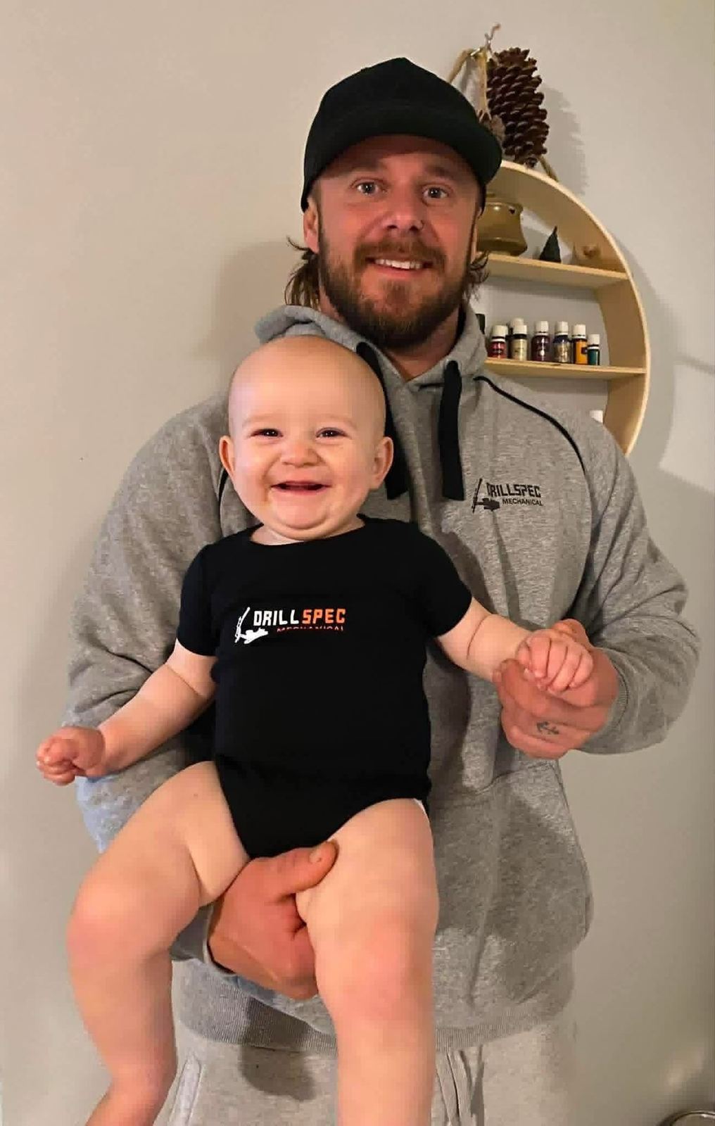 Drillspec Mechanical director Zac Parsons holding his baby in Drillspec clothing