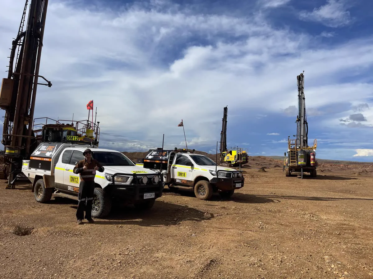 Drillspec crew member with DM12 and DM18 utes and drill rigs on site