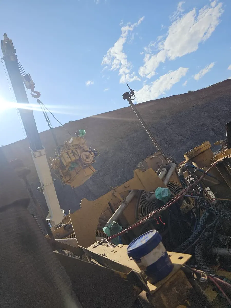Engine being craned out of a machine against a blue sky