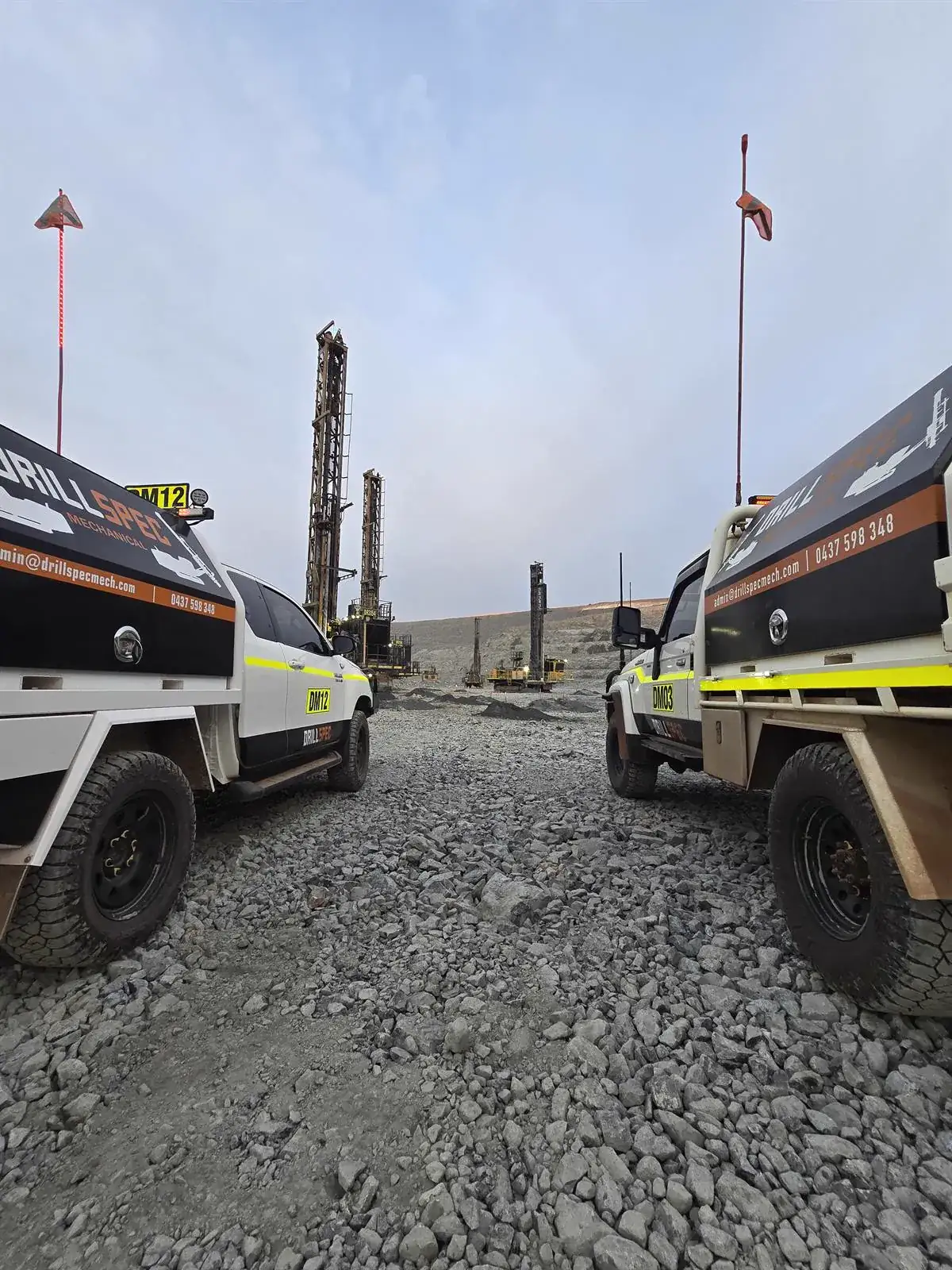 Two Drillspec service utes on the bench with production drill rigs behind at first light