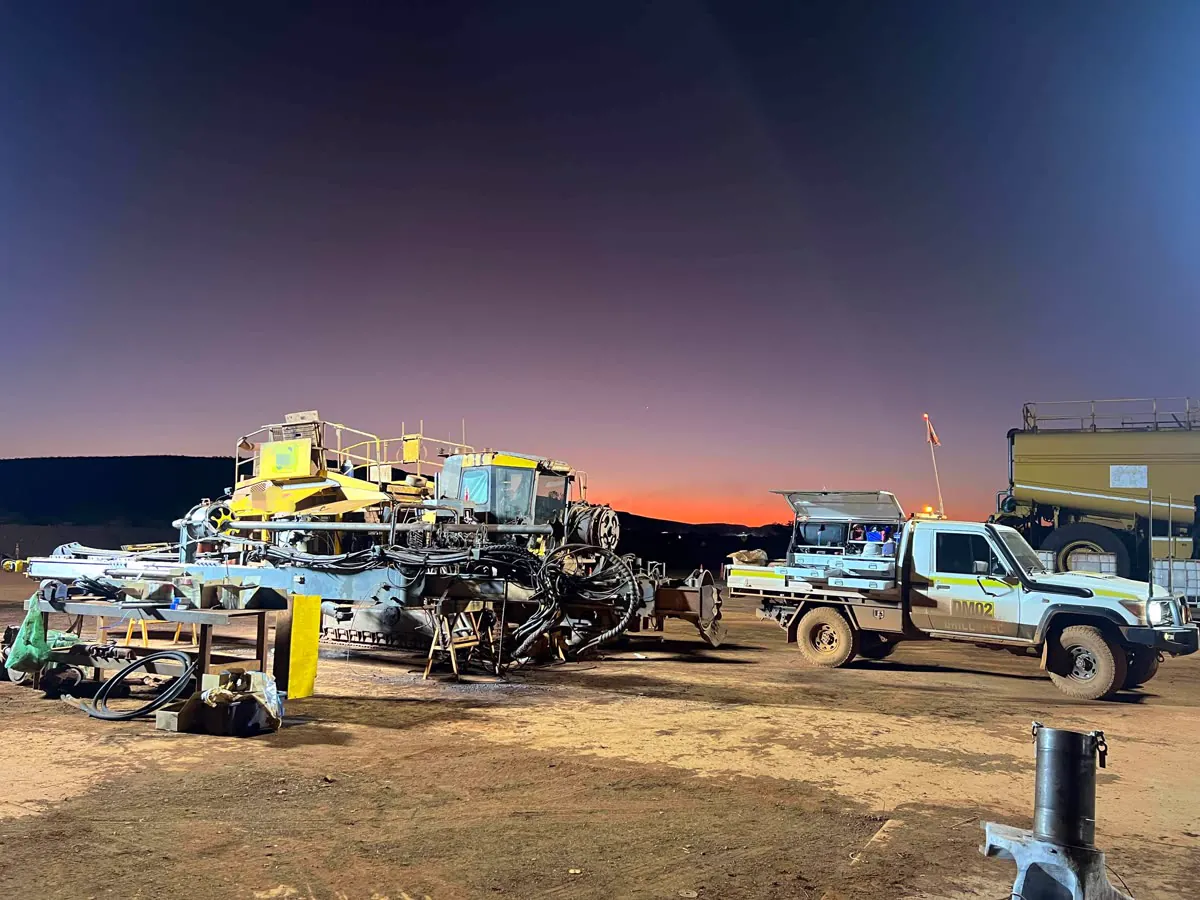 Drillspec DM02 ute beside a stripped drill rig under lights at night
