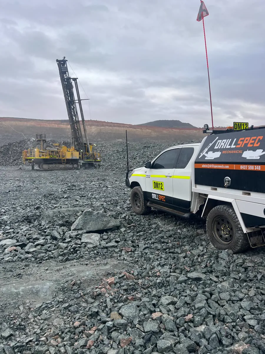 Drillspec DM12 ute on blast rock with drill rig DR236 working behind