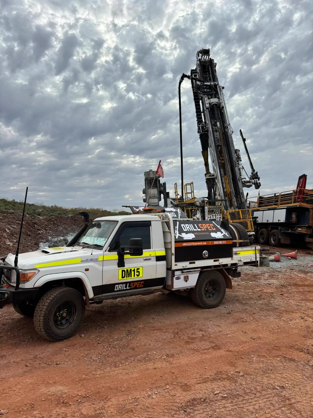 Drillspec DM15 service ute alongside an exploration rig under cloudy sky
